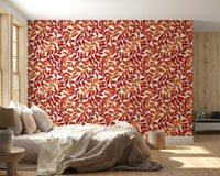 Rustic Leaves wallpaper with red and orange foliage behind a cream bed in a warm bedroom