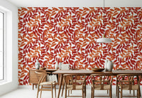 Rustic Leaves wallpaper in red and orange behind a wooden table and wishbone chairs in a dining room