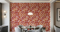Rustic Leaves wallpaper in red and orange behind a round dining table and grey chairs in a dining room