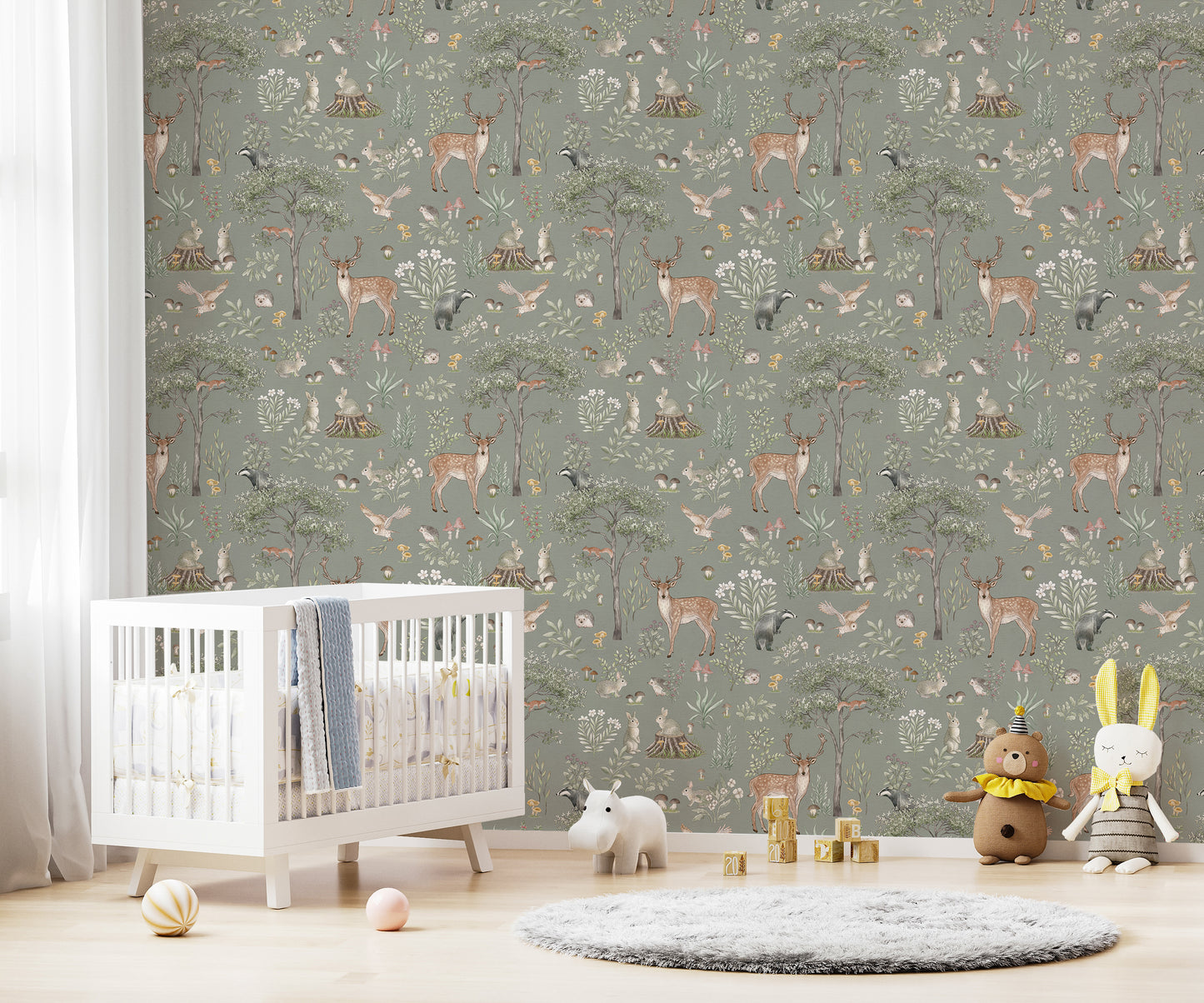 Sage Green Wildlife wallpaper in a nursery with a white crib, grey rug and bear and bunny plush toys