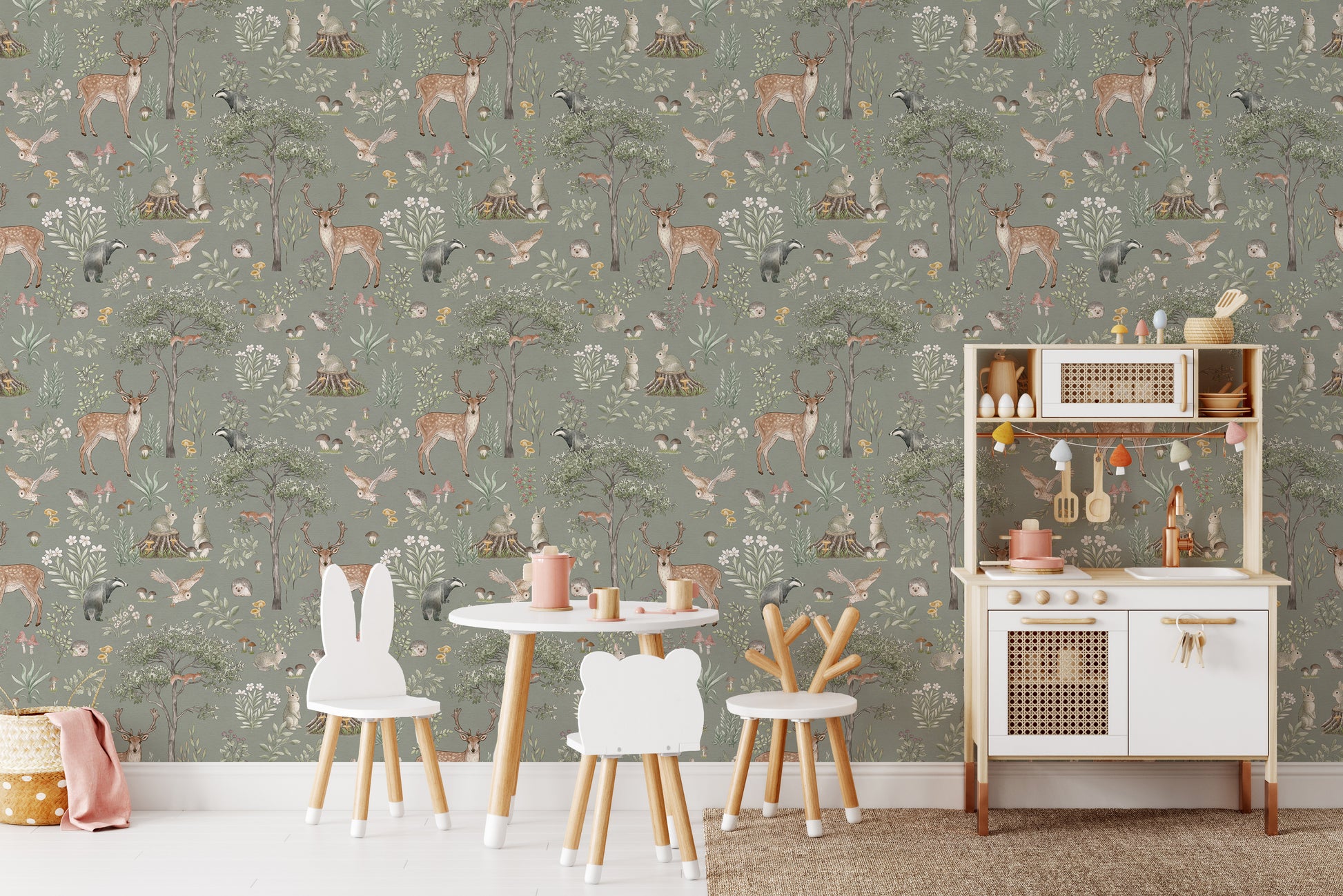 Sage Green Wildlife wallpaper behind a round play table and white kitchen in a green woodland nursery