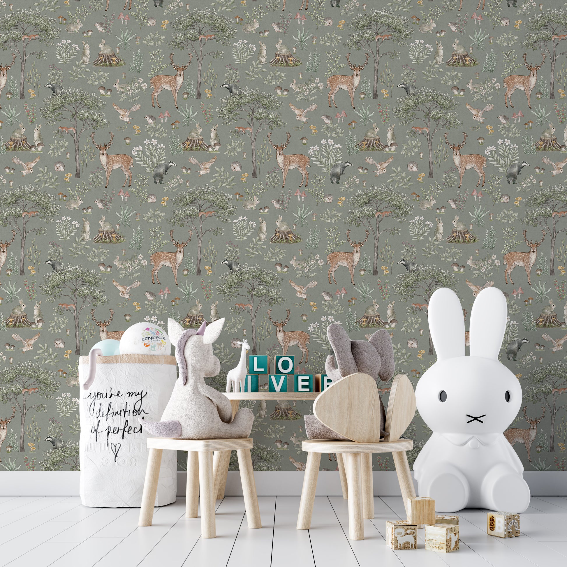 Sage Green Wildlife wallpaper in a nursery with a white Miffy bunny lamp, plush unicorn and wooden stools