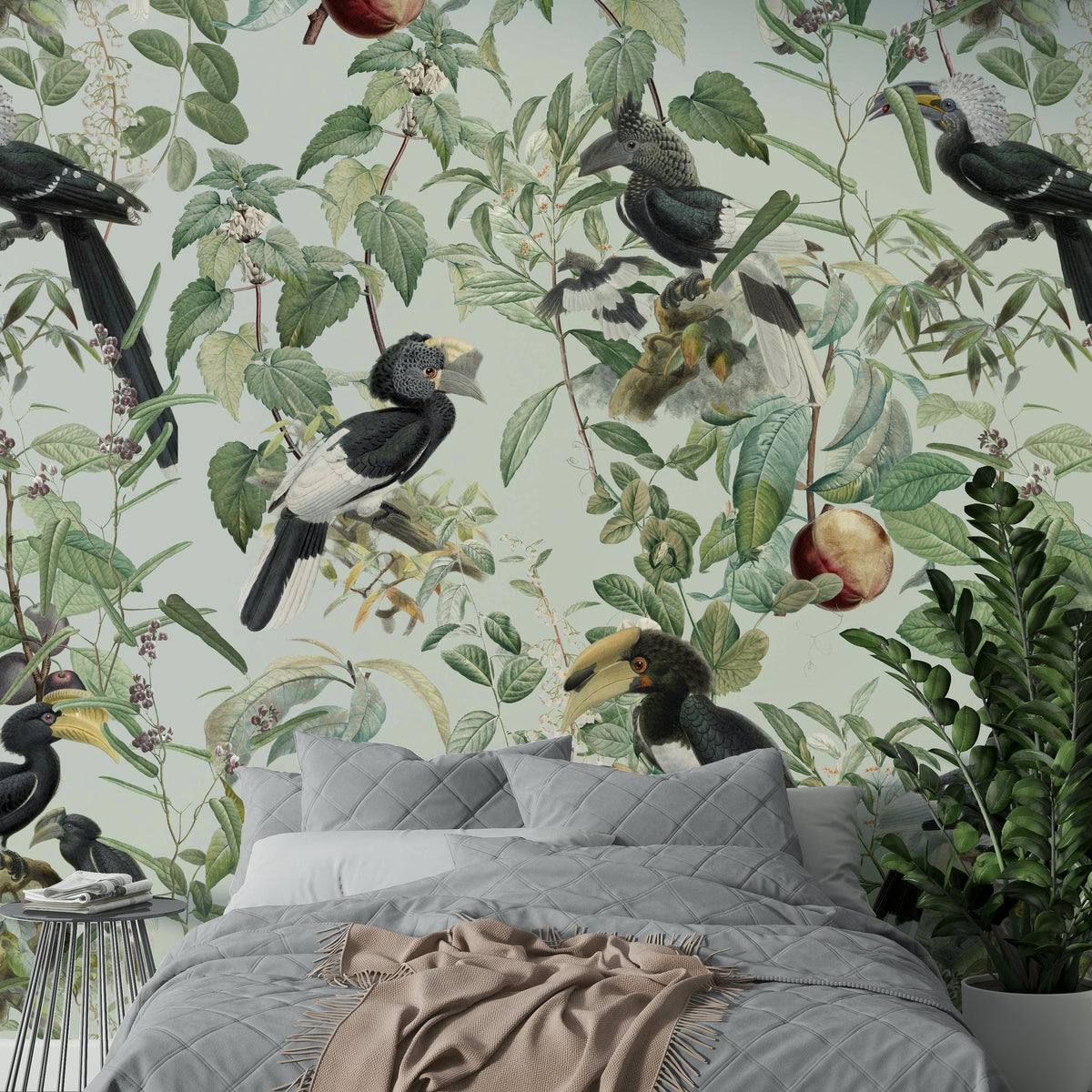 Savannah wallpaper mural with hornbill birds and green foliage behind a grey quilted bed and potted fern