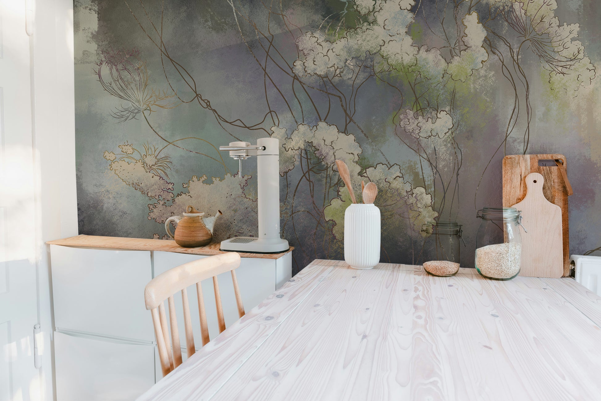 Wildflower Whisper wallpaper mural in muted green tones behind a kitchen counter with teapot, coffee maker and cutting boards
