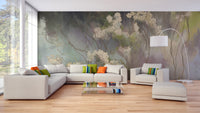 Wildflower Whisper wallpaper mural with painterly cream blooms on a moody green ground behind a beige sectional sofa in a living room
