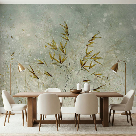 Whispering Grass wallpaper mural with golden grass on a sage wall behind a wood dining table and brass floor lamps