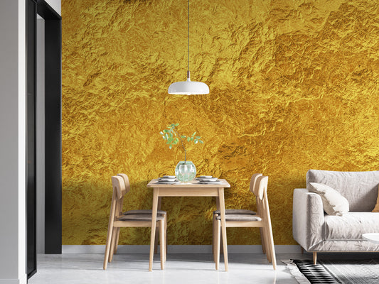 Luxurious Golden Texture wallpaper mural in shiny gold foil behind a small wood dining table and white sofa