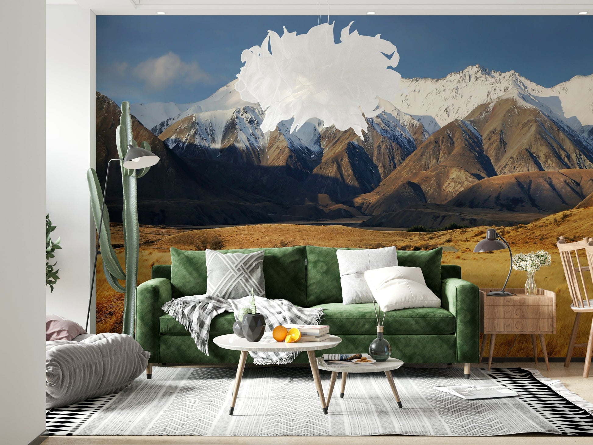 Snowy Peaks Path wallpaper mural of snowy peaks and golden valley behind a green velvet sofa in a living room