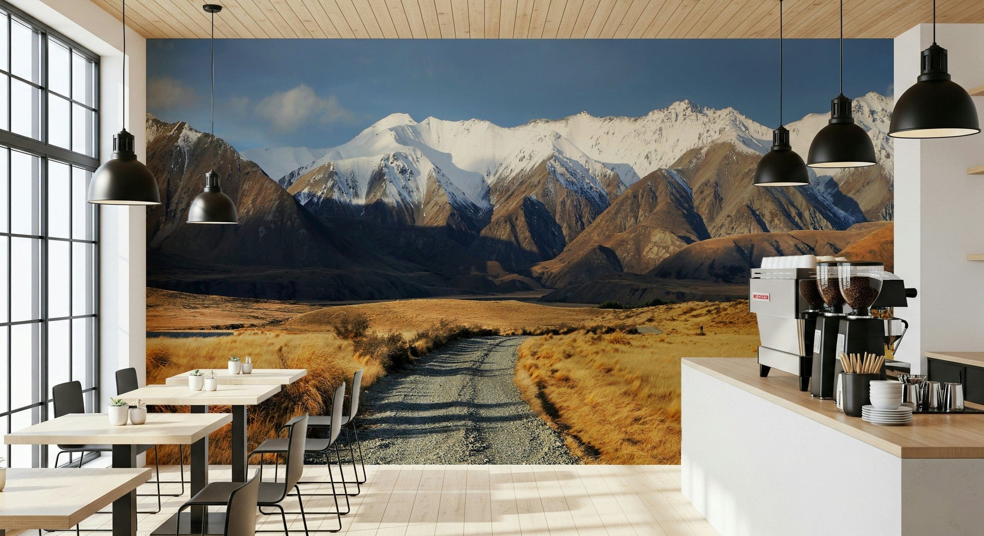 Snowy Peaks Path wallpaper mural of snowy mountains and a gravel path on a cafe wall with wood tables and pendants