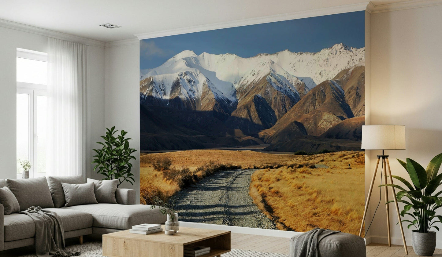 Snowy Peaks Path wallpaper mural of snowy peaks and a valley path behind a gray sectional and tripod lamp living room
