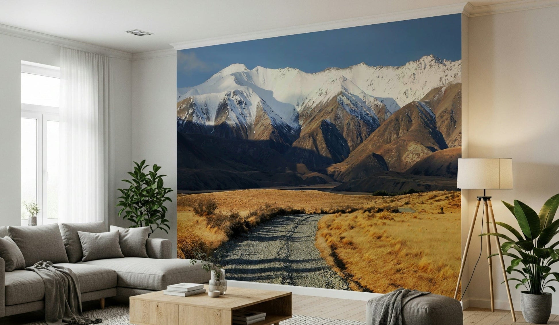 Snowy Peaks Path wallpaper mural of snowy peaks and a valley path behind a gray sectional and tripod lamp living room