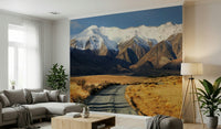Snowy Peaks Path wallpaper mural of snowy peaks and a valley path behind a gray sectional and tripod lamp living room