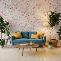 Soft Floral Pink Meadow wallpaper mural of pink blooms behind a teal sofa with yellow pillows and plants in a living room