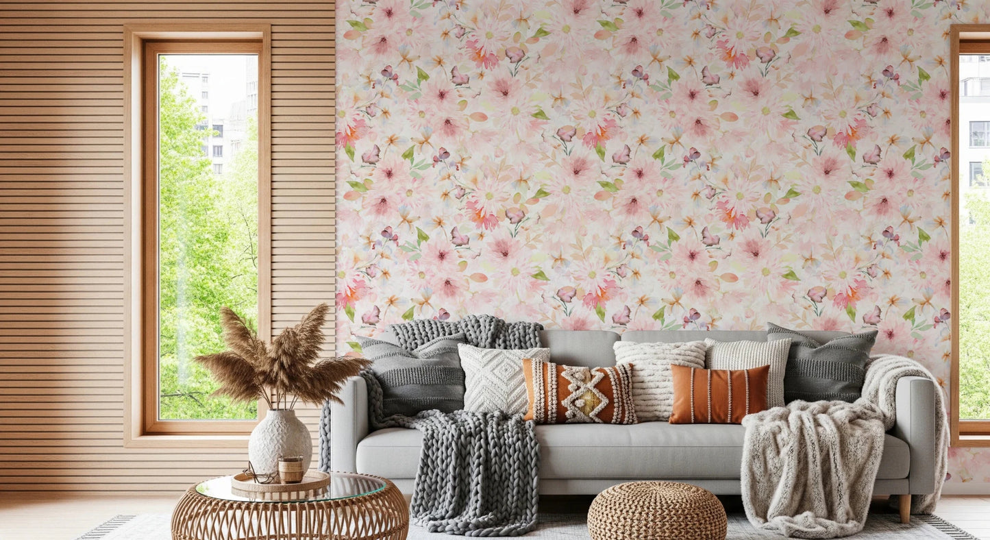 Soft Floral Pink Meadow wallpaper mural in blush florals behind a grey sofa with knit throws and rust pillows in a living room