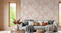 Soft Floral Pink Meadow wallpaper mural in blush florals behind a grey sofa with knit throws and rust pillows in a living room