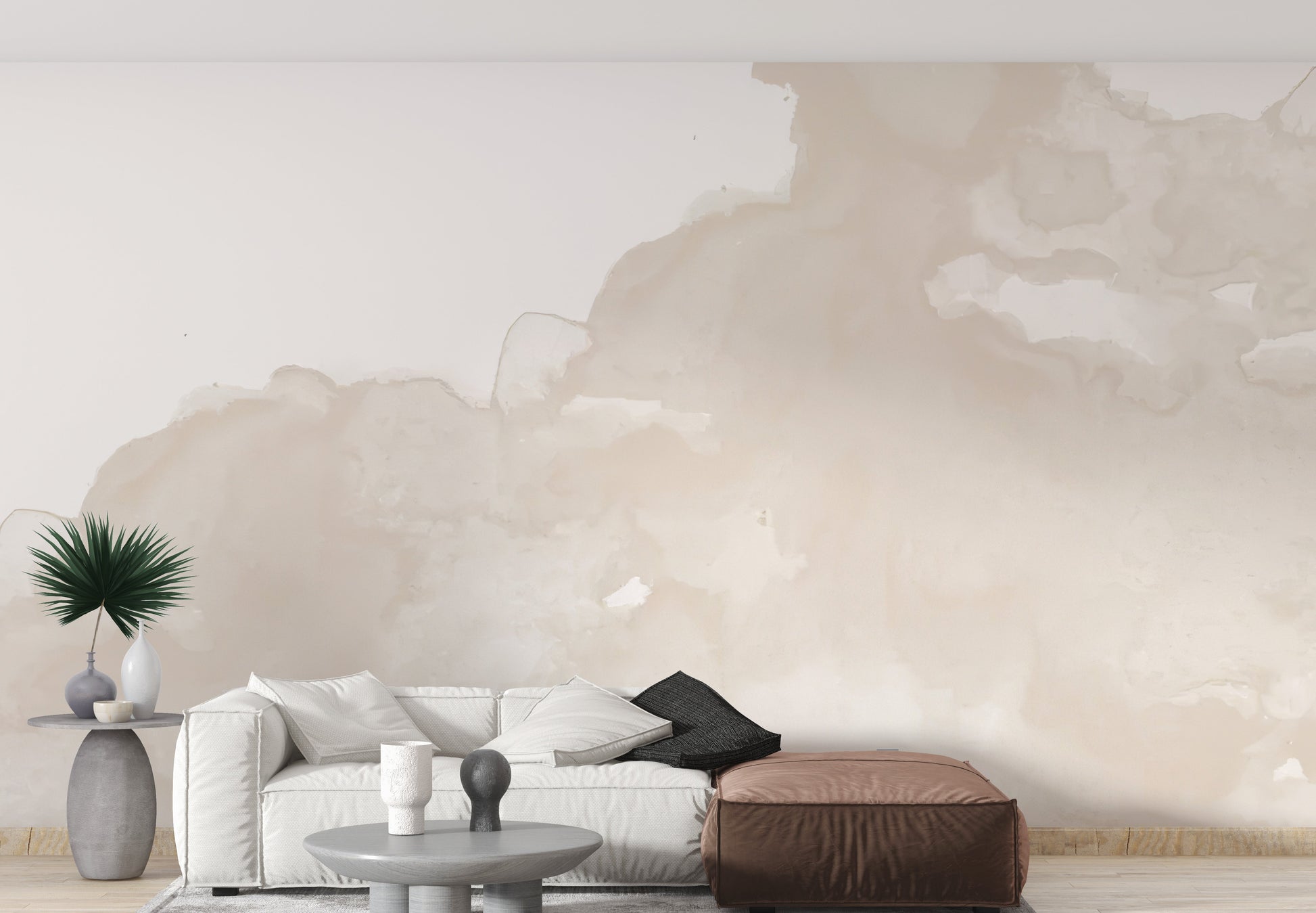 Abstract Watercolor wallpaper mural in soft beige washes behind a white sofa and brown leather pouf in a living room