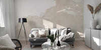 Abstract Watercolor wallpaper mural in cream tones behind a gray sofa and black tripod lamp in a living room