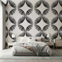 Starburst Deco wallpaper of black starbursts on cream behind a bed with blush bedding and wood nightstands