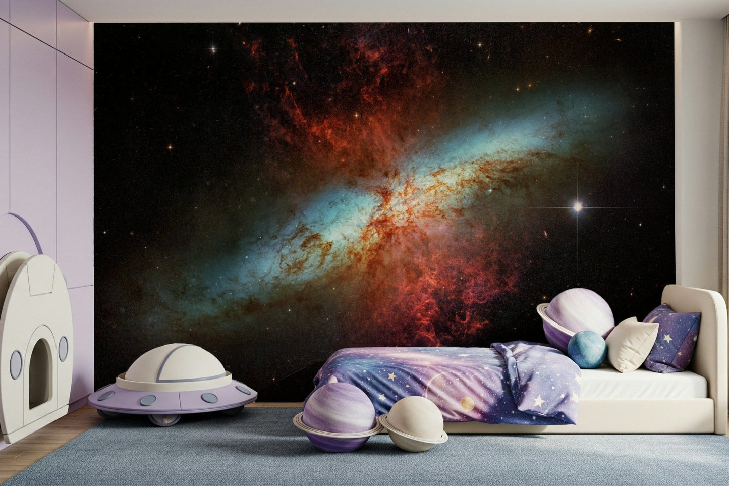 Stardust Symphony wallpaper mural of a red and blue nebula in a kids room with a purple UFO and planet cushions