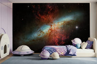 Stardust Symphony wallpaper mural of a red and blue nebula in a kids room with a purple UFO and planet cushions