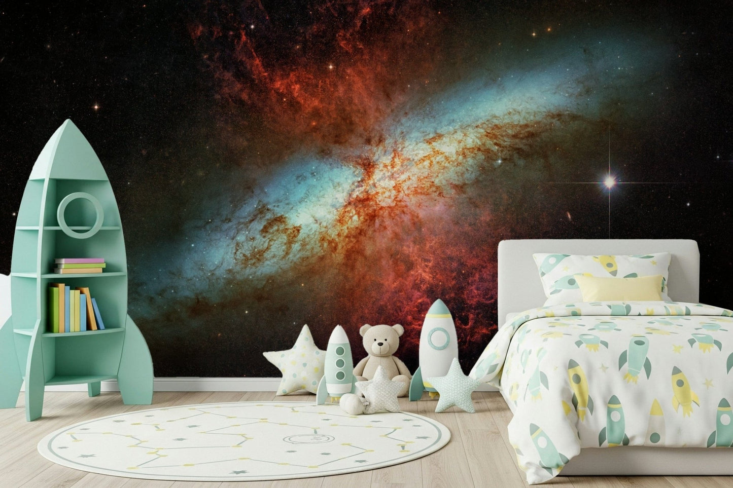 Stardust Symphony wallpaper mural with a glowing nebula in a kids room with a mint rocket shelf and rocket bedding