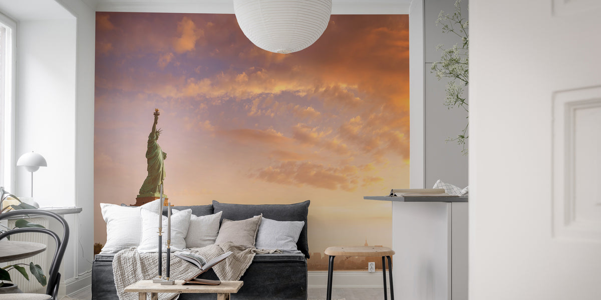 Statue of Liberty wallpaper at peach sunset behind a grey sofa with white cushions in a living room