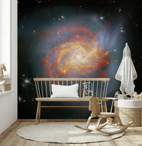 Stellar Canvas wallpaper mural with a swirling galaxy behind a wooden bench and toy basket in a nursery