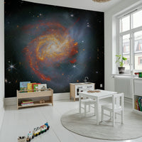 Stellar Canvas wallpaper mural with a glowing galaxy in a kids playroom with a white play kitchen and books