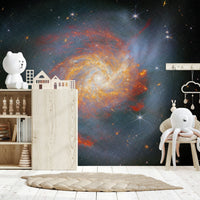 Stellar Canvas wallpaper mural of a blue and orange galaxy in a kids room with a bear lamp and toy shelf