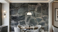 Stone Facade wallpaper mural behind a round dining table and grey chairs lit by a dome pendant