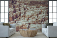 Striated Rock Face wallpaper mural of banded stone between two white armchairs and a round wood coffee table