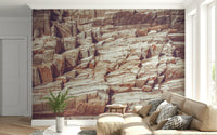 Striated Rock Face wallpaper mural of layered cliff stone behind a tan sectional sofa in a bright living room