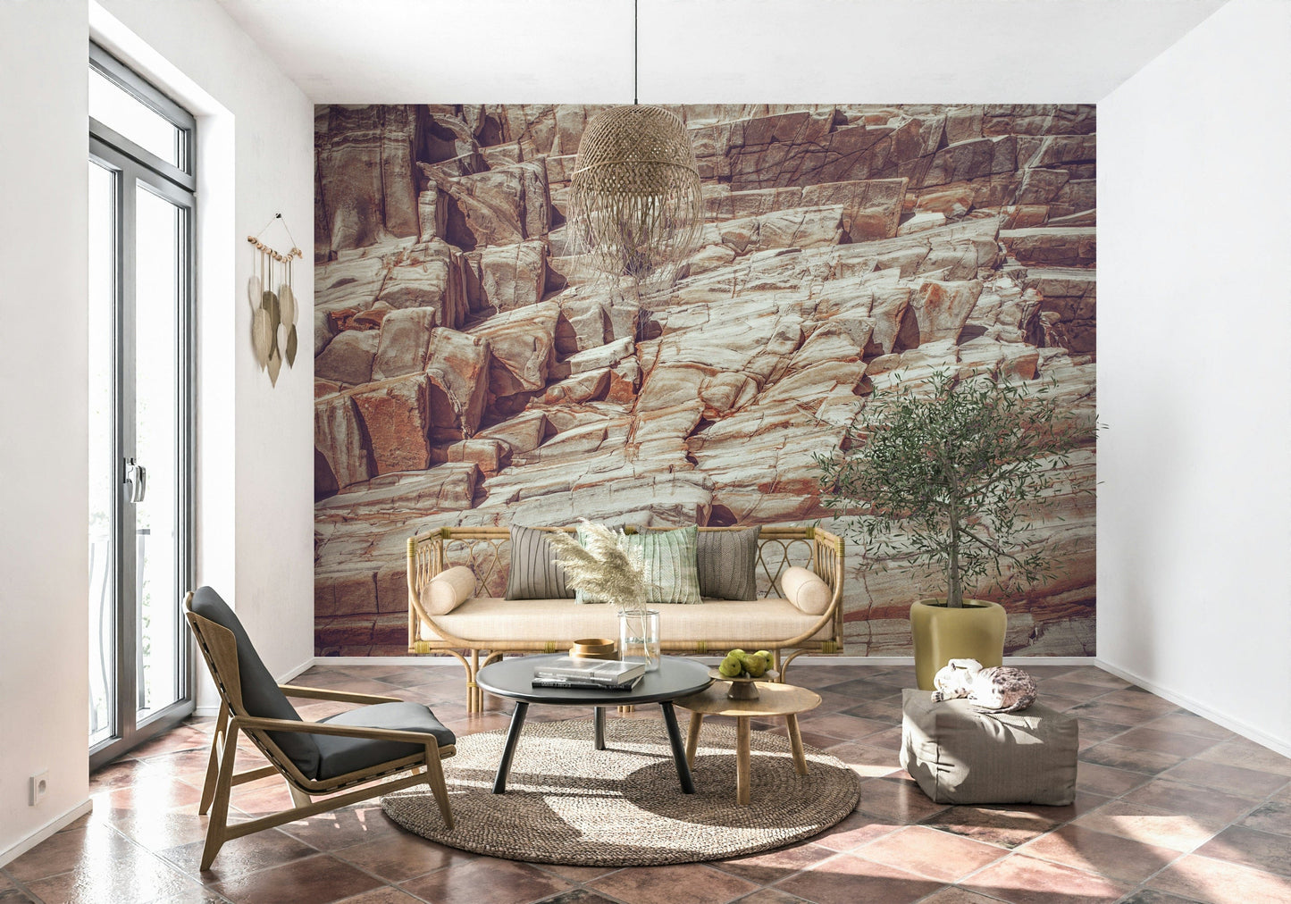 Striated Rock Face wallpaper mural of red and cream rock behind a cane bench sofa and olive tree on tile floor