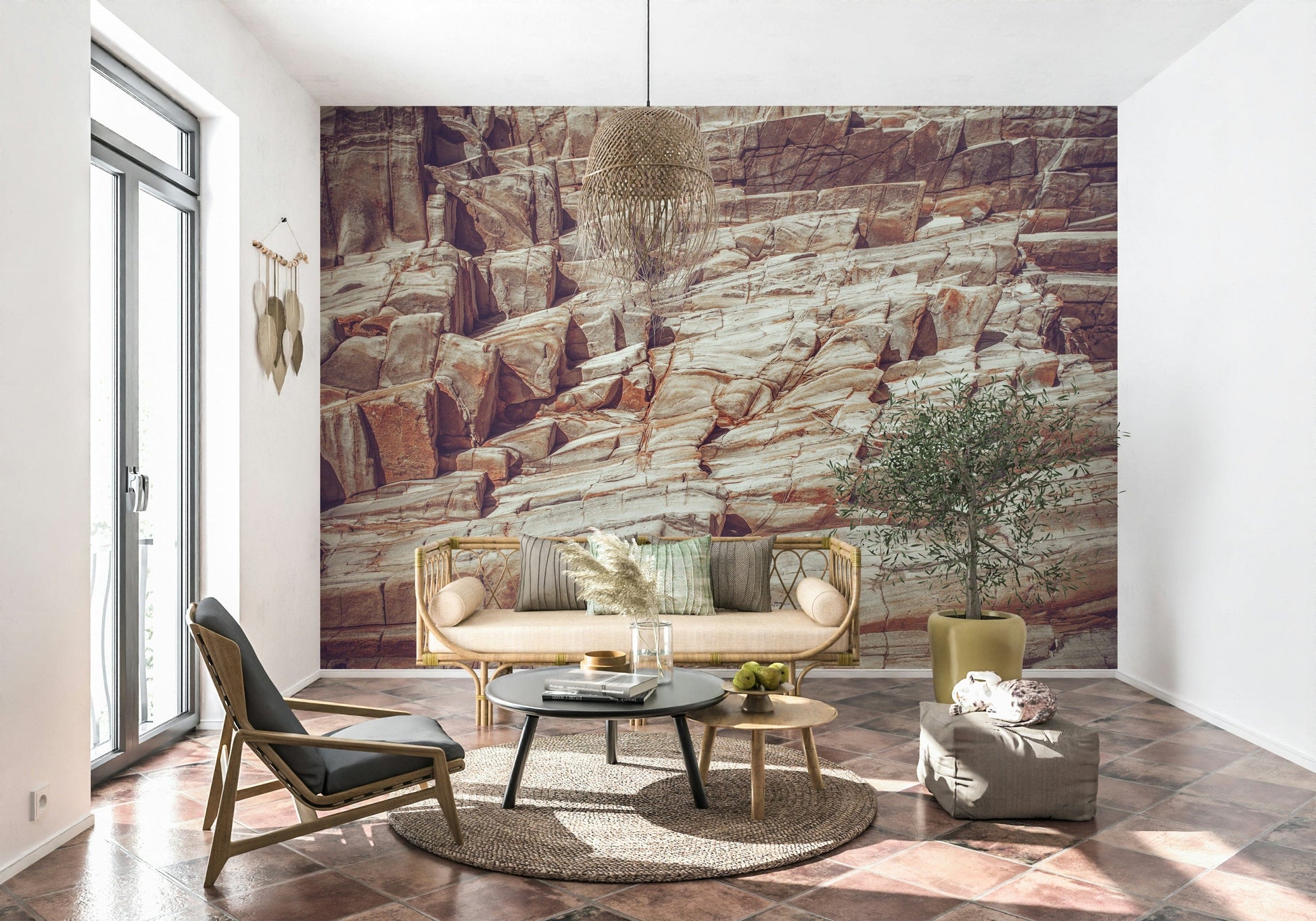Striated Rock Face wallpaper mural of red and cream rock behind a cane bench sofa and olive tree on tile floor