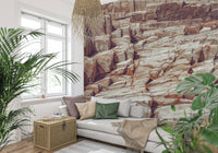 Striated Rock Face wallpaper mural of reddish rock strata behind a grey sofa with green cushions by a window