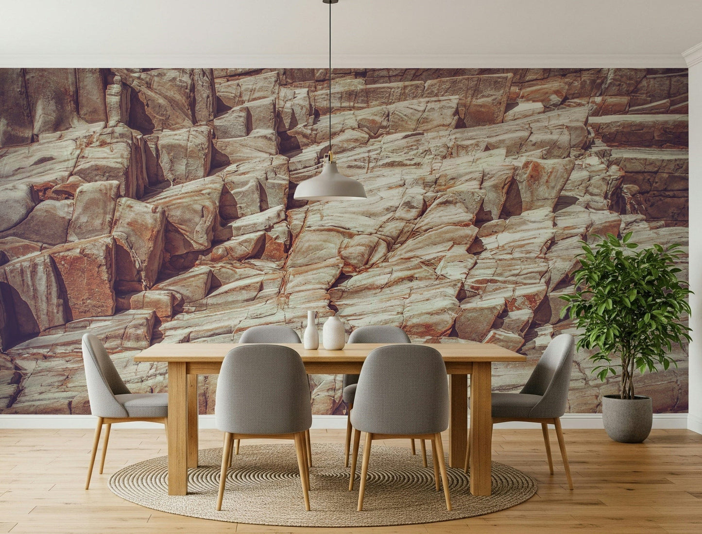 Striated Rock Face wallpaper mural of cream and rust rock layers behind a wood dining table and grey chairs