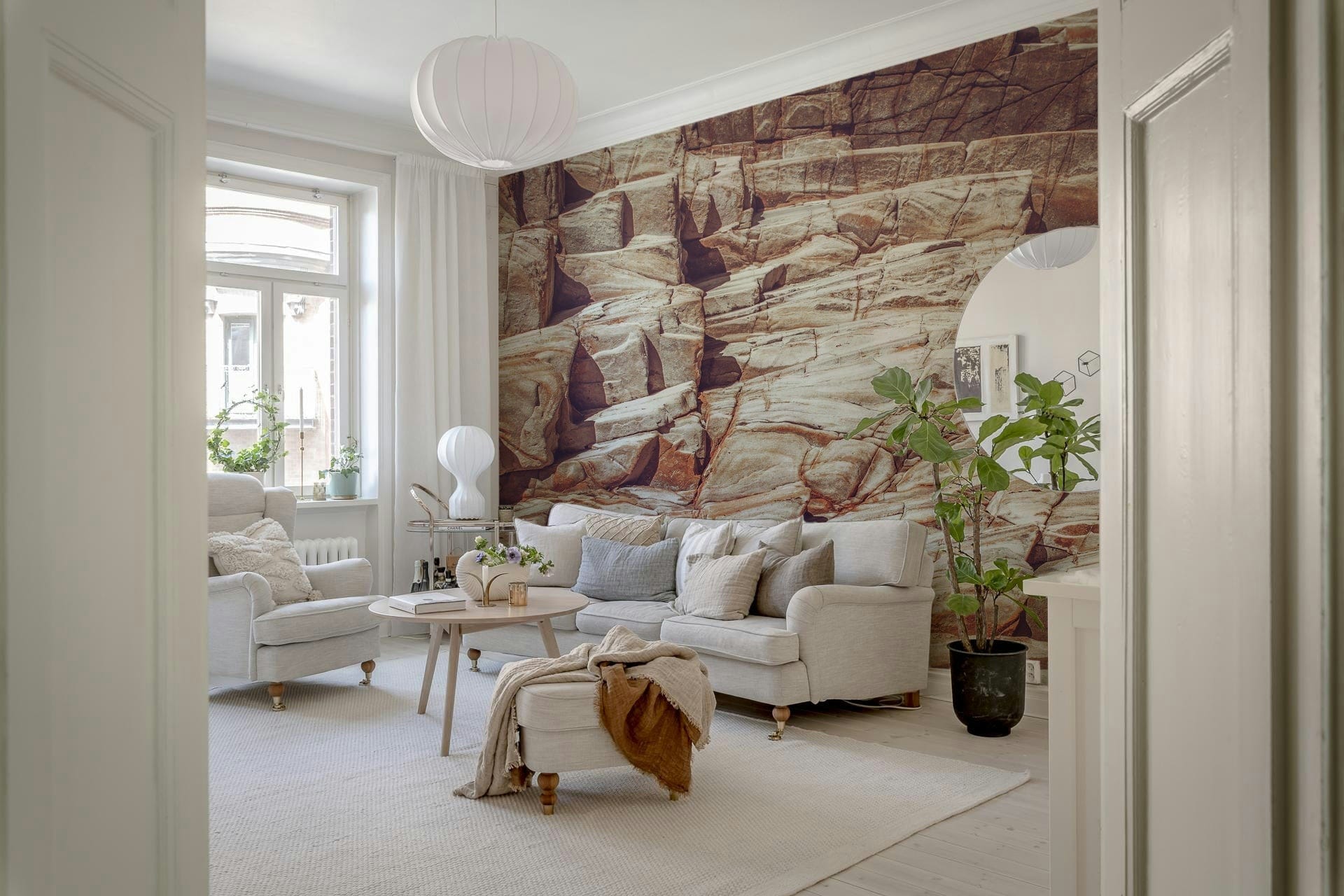 Striated Rock Face wallpaper mural of red rock strata behind a cream sofa with a fiddle-leaf fig in a living room