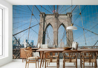 Strolling Across the Brooklyn Bridge wallpaper mural in a dining room with a wood table and woven wishbone chairs