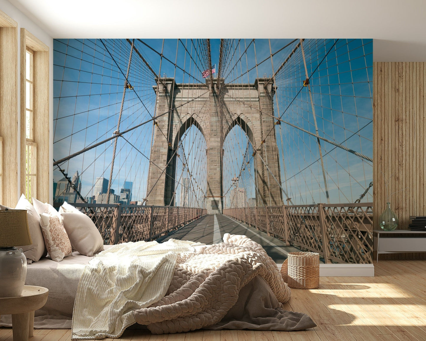 Strolling Across the Brooklyn Bridge wallpaper mural behind a low bed with cream knit bedding in a wood-panelled bedroom