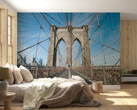 Strolling Across the Brooklyn Bridge wallpaper mural behind a low bed with cream knit bedding in a wood-panelled bedroom