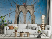 Strolling Across the Brooklyn Bridge wallpaper mural of the cable-strung tower above a white sofa with a tan pillow