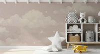 Sweet Dreams Blush wallpaper mural of pink clouds and stars in a nursery with a white toy shelf and star cushion