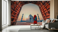 Woman in red sari gazing at Taj Mahal at sunset wallpaper mural arch frame.