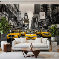 Taxi Rush Hour wallpaper mural of yellow cabs in Times Square behind a white sofa and fiddle-leaf plants in a living room