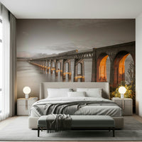 Tay Rail Bridge wallpaper mural with glowing arches behind an upholstered bed with grey bedding in a bedroom