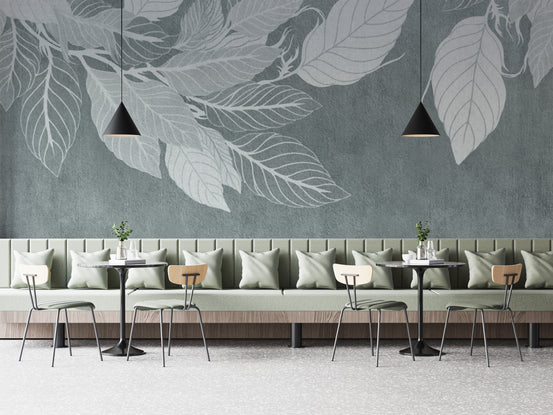 Elegant Teal Botanical Leaf wallpaper mural with pale leaf silhouettes behind a sage banquette and bistro tables in a cafe