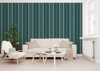 Teal Stripe wallpaper with cream vertical lines behind a beige sofa, rattan chair and leafy plant in a living room