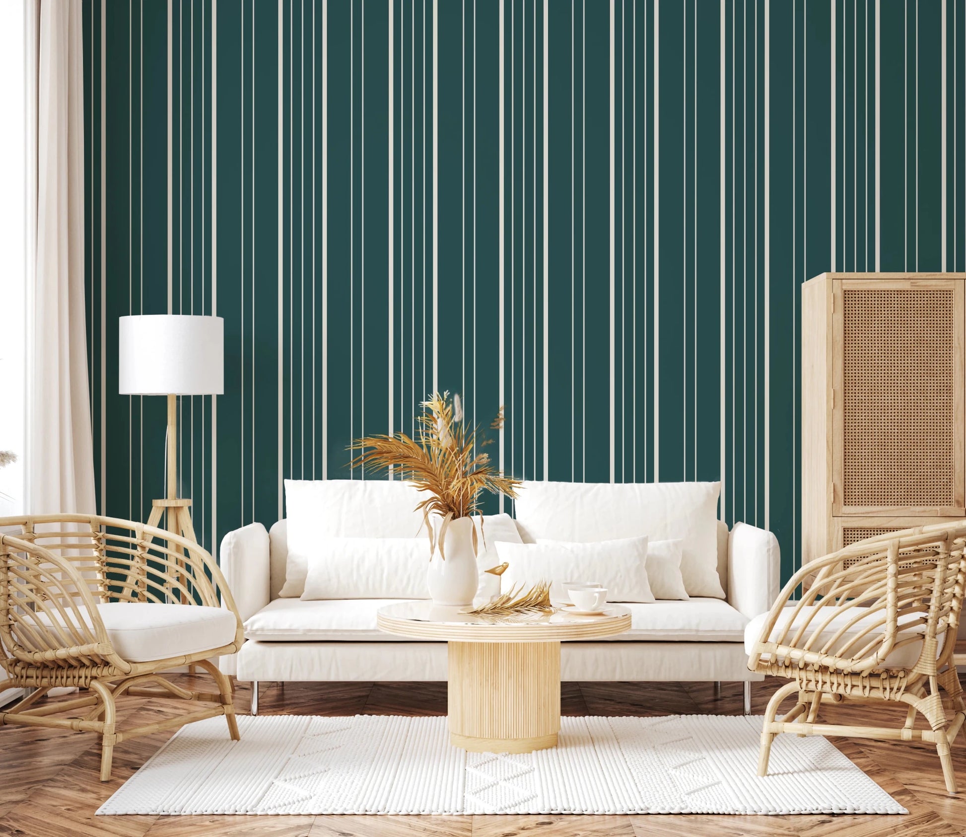 Teal Stripe wallpaper with cream lines behind a white sofa, rattan chairs and pampas grass in a cozy living room