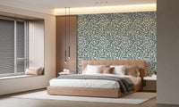 Teal Vines wallpaper of teal leaves behind a tan leather bed with white bedding and linear pendant lights