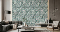 Teal Vines wallpaper of teal leaves behind a charcoal sectional sofa with glass globe pendant lights